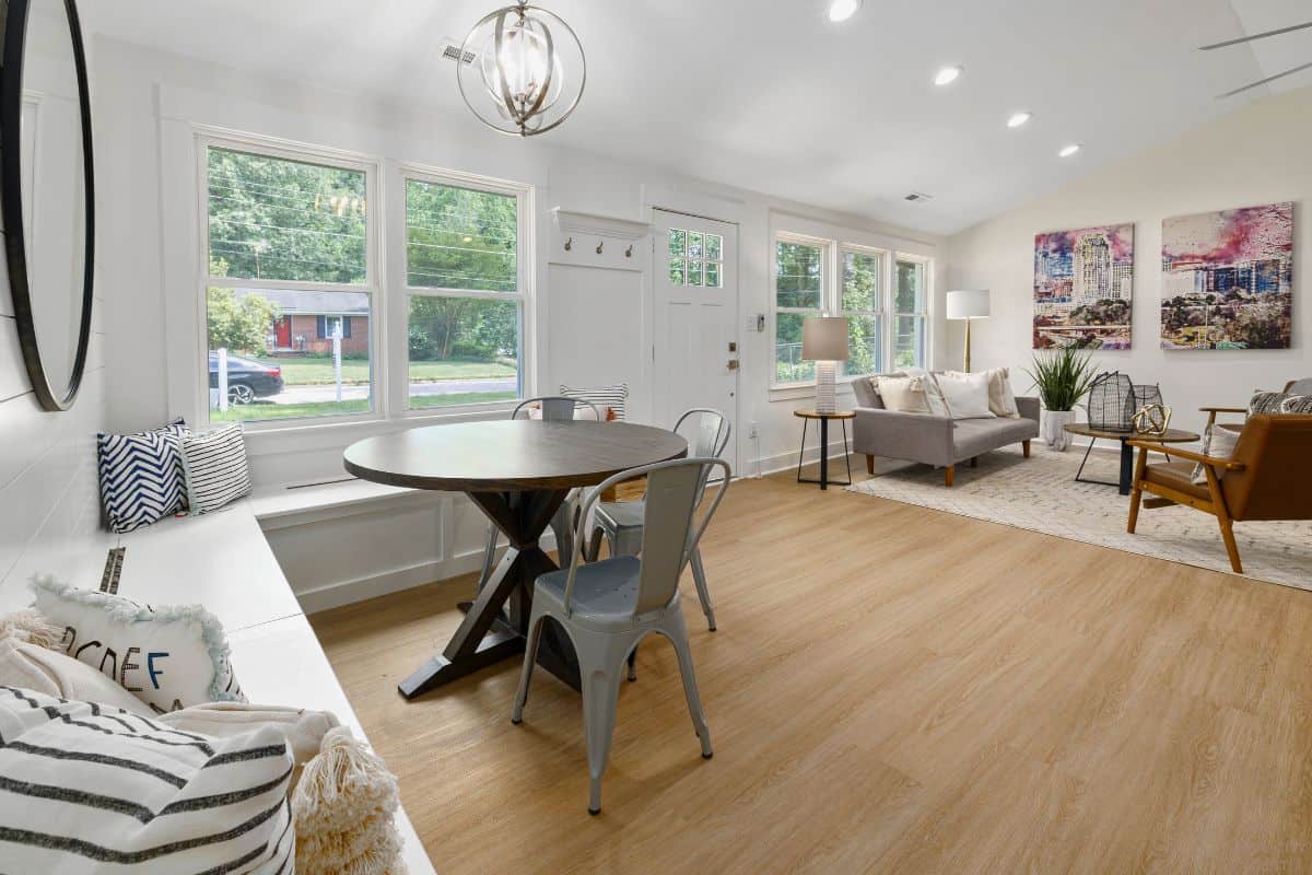 Sunlit dining nook opening into a living room with a sofa and armchairs